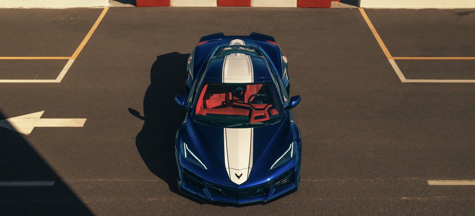 2027 Chevrolet Corvette Grand Sport in blue, overhead front view with white racing stripes and red interior