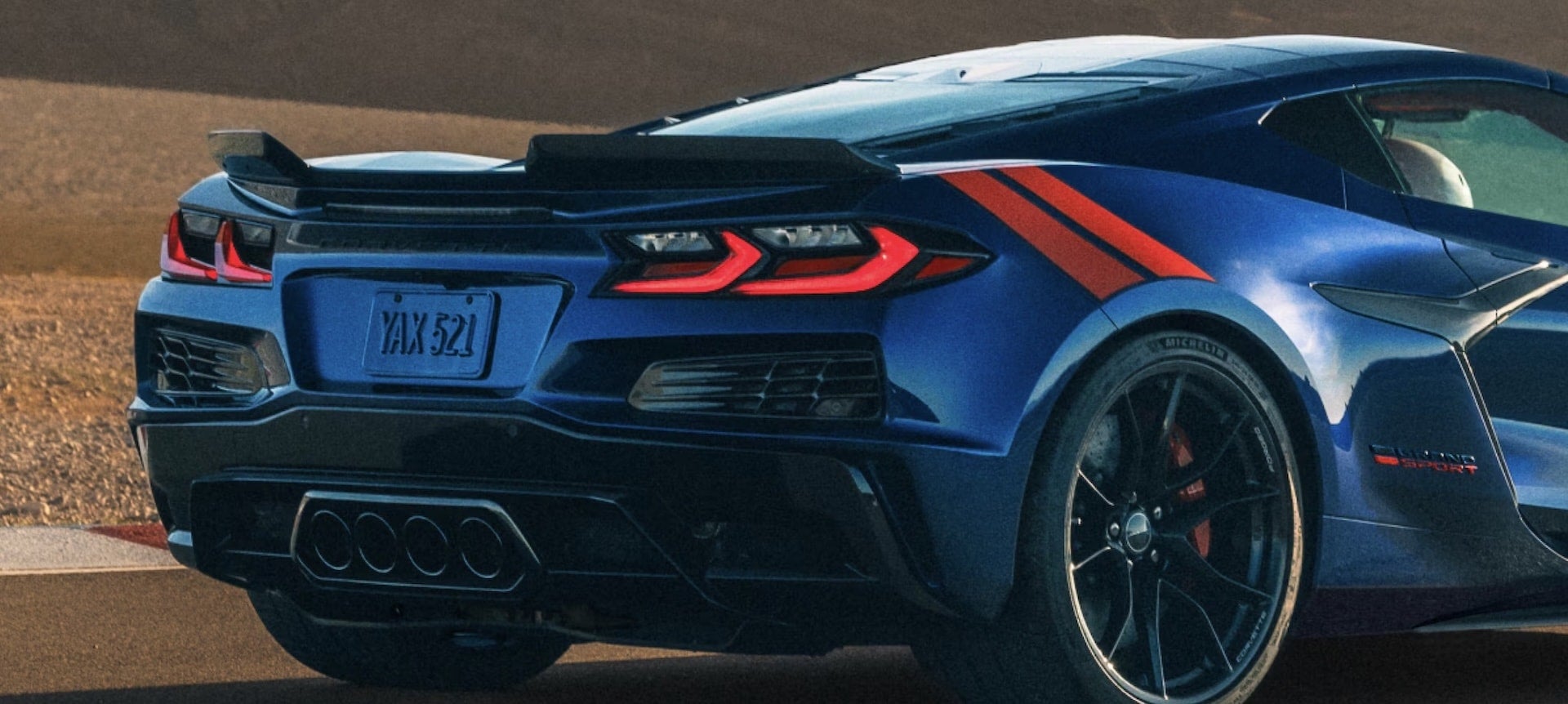 2027 Chevrolet Corvette Grand Sport rear closeup in blue with quad center exhaust and orange stripes