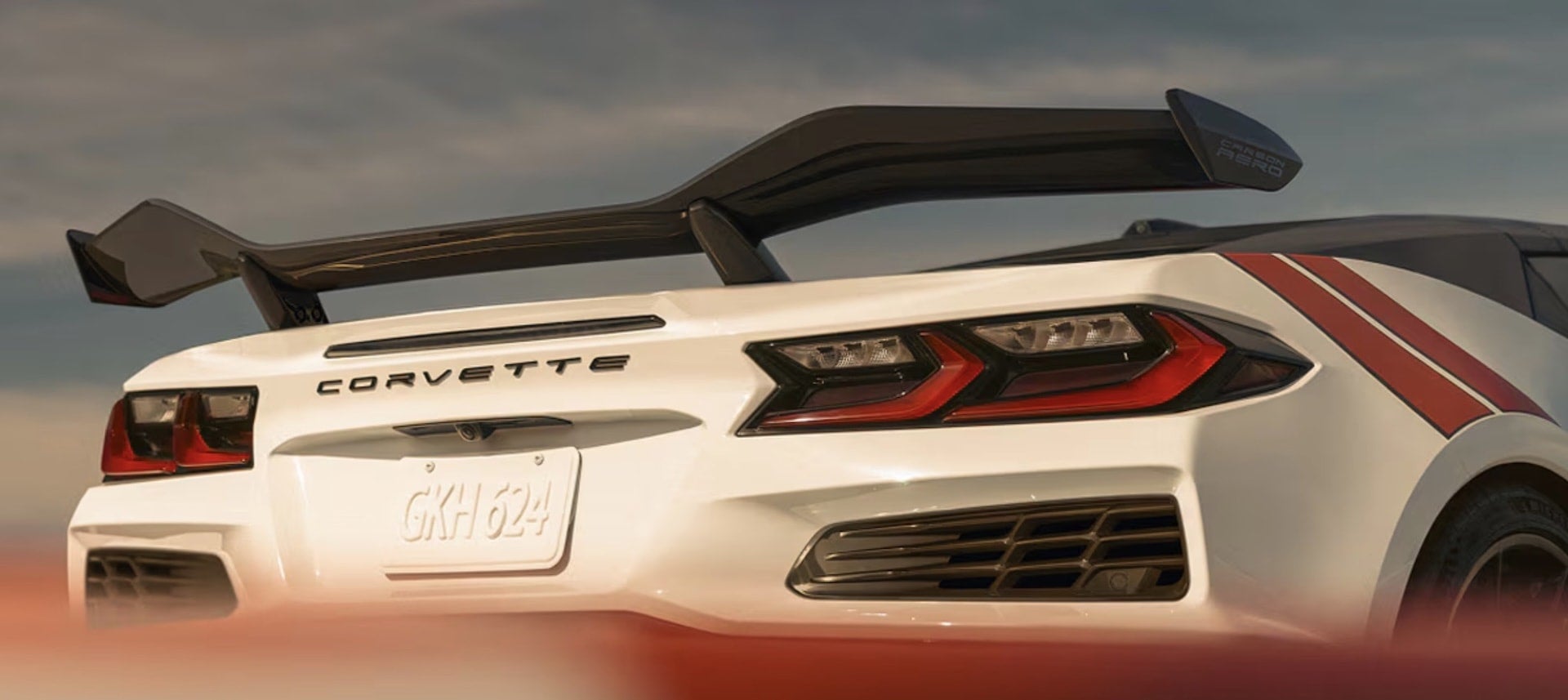 2027 Chevrolet Corvette Grand Sport rear closeup in white with the carbon fiber aero wing and red racing stripes