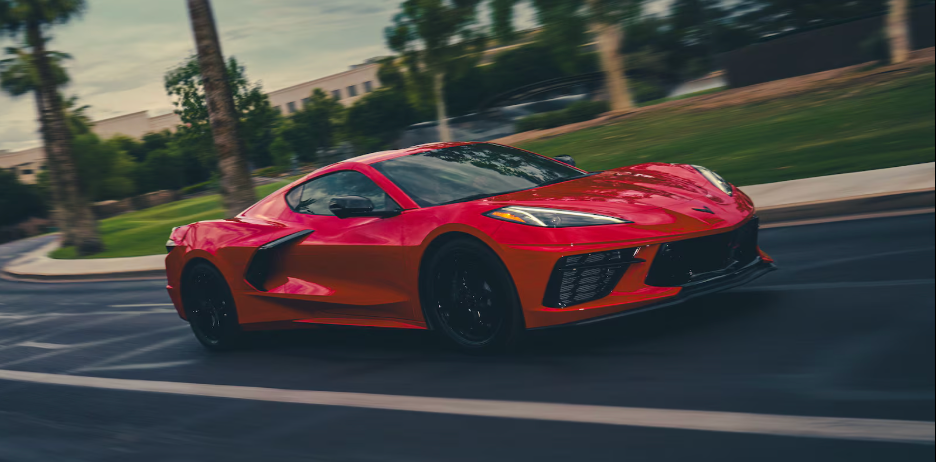 Red Chevrolet Corvette Stingray coupe in motion on a road
